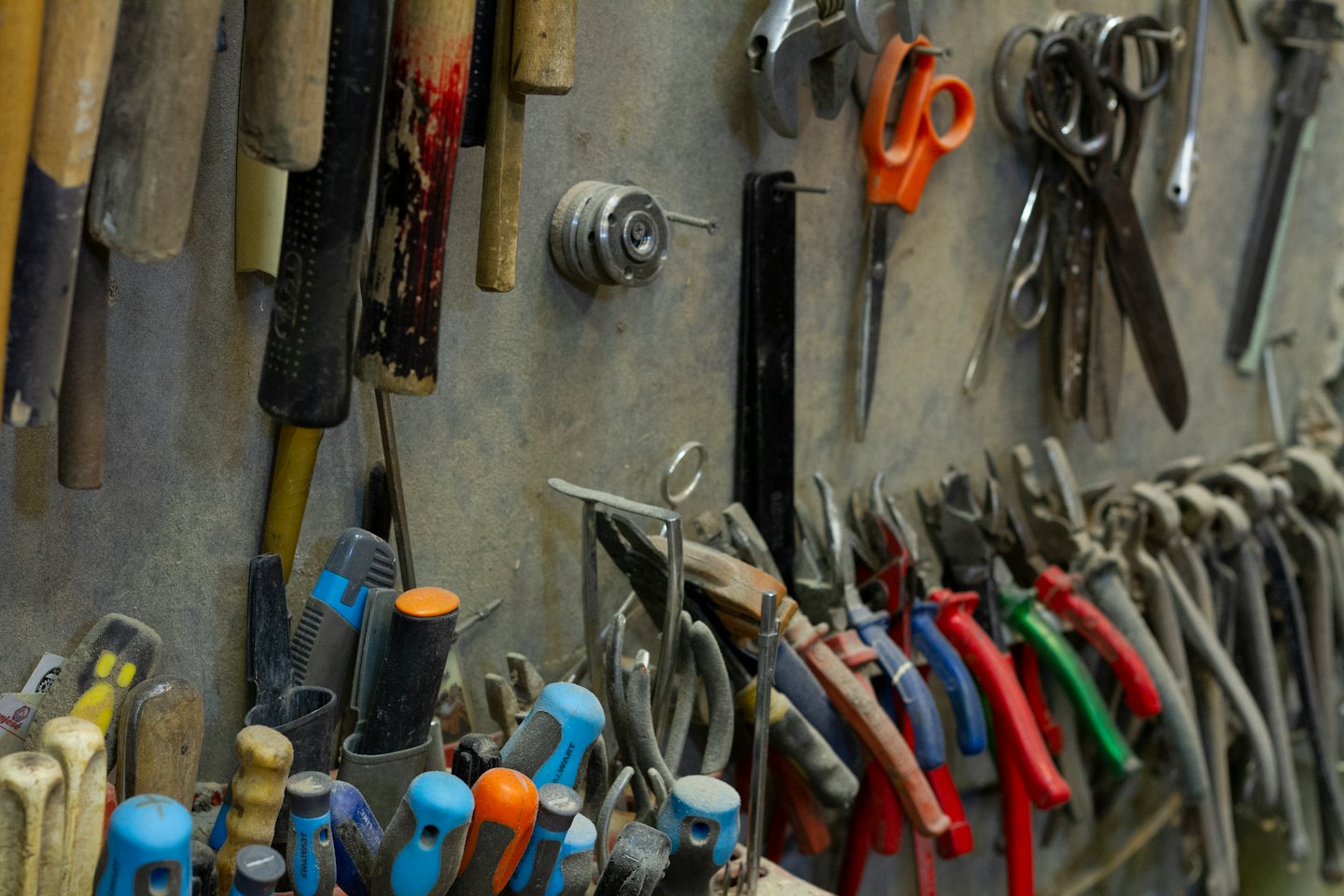 Various hand tools hanging on a workshop wall.